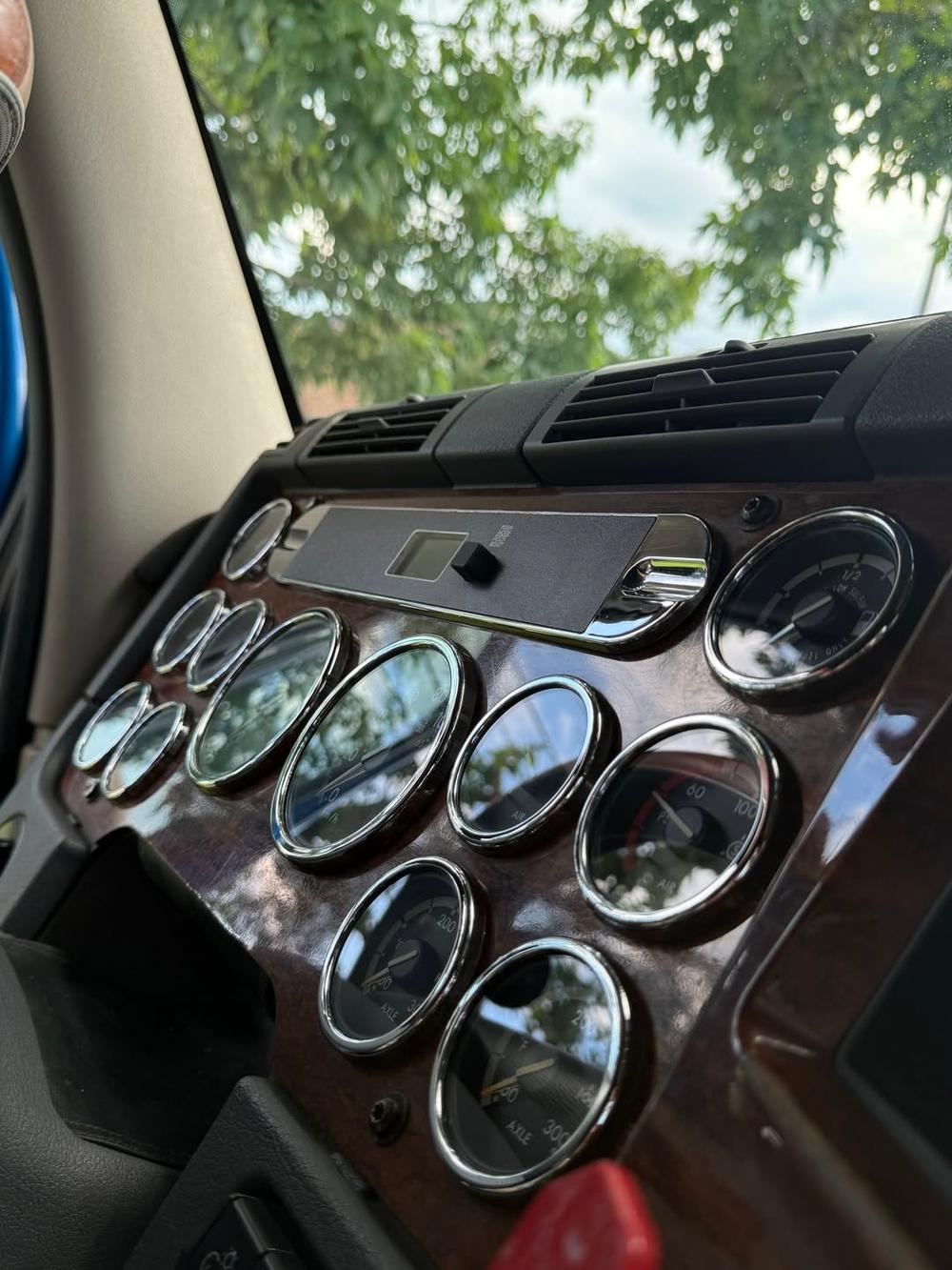 Detailed semi-truck cab dashboard with polished chrome gauges and wood-grain trim - mobile detailing by A&F Auto Detailing